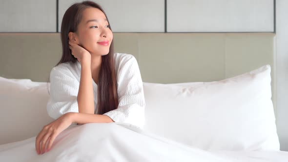 Asian woman relax on bed in bedroom interior