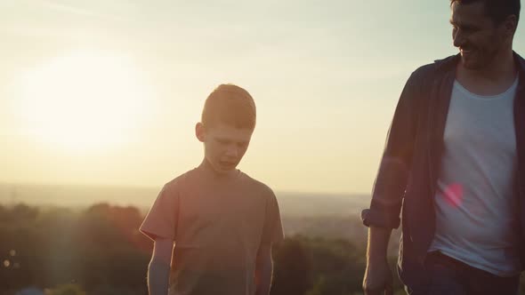 Little boy walking with dad at the meadow during the sunset. Shot with RED helium camera in 4K.