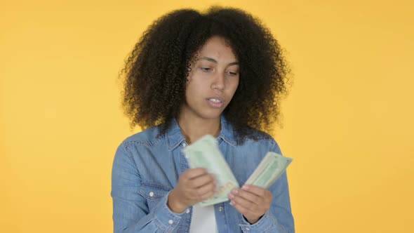 African Woman Counting Dollars Yellow Background