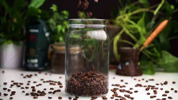 Slow Motion Empty Transparent Jar Filled with Coffee Beans on White Table with Coffee Beans Lay on