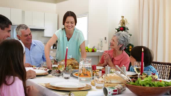 Mother bringing turkey to dinner table for christmas