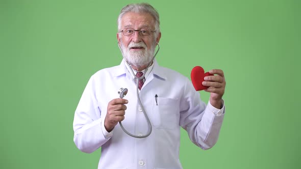 Handsome Senior Bearded Man Doctor Against Green Background