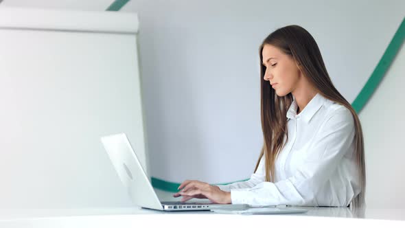 Beautiful Businesswoman Working with Laptop in White Office