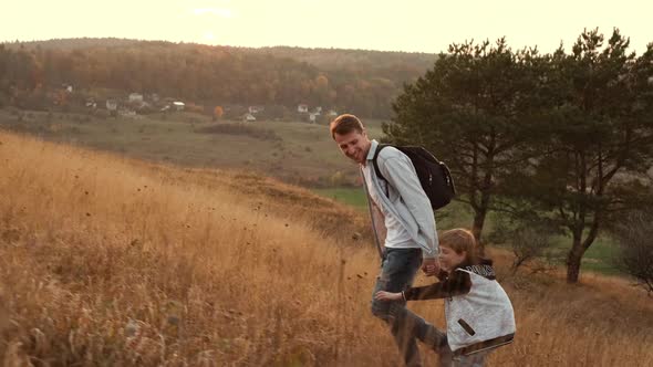 Walk In The Nature Of Dad And Son. Dad And Son Climb The Hill.