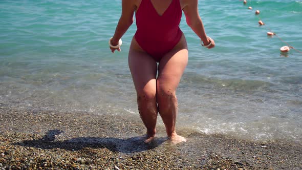 Young Woman with Long Hair in a Red Swimsuit and Bracelets in Boho Style Enjoying the Waves on the