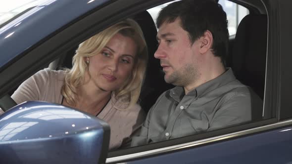 Husband and Wife Sitting in a New Car at the Dealership Examining Interior