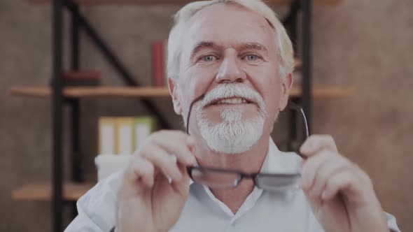 Portrait of a Friendly Looking Retired Senior Man Taking Off His Glasses and Smiling Cheerfully