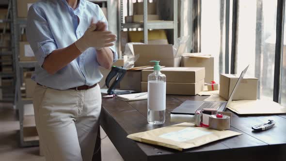 Female Warehouse Worker Wearing Gloves Using Sanitizer at Work