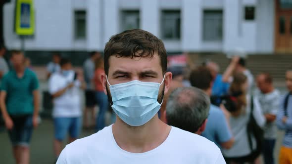 Portrait of riot activist in covid-19 face mask among picketing crowd on streets