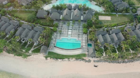 Aerial view of a tropical beach resort with swimming pool and beachfront accommodation during sunris