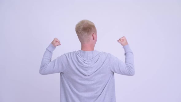 Rear View of Happy Young Blonde Man with Fists Raised