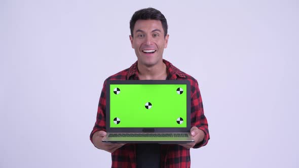 Happy Young Hispanic Hipster Man Showing Laptop and Looking Surprised