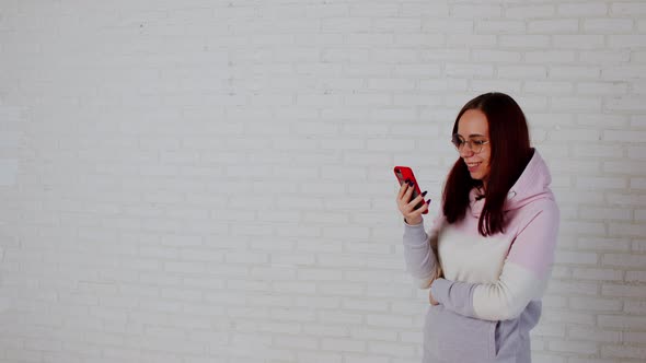 Young Woman Using Smartphone Near Wall