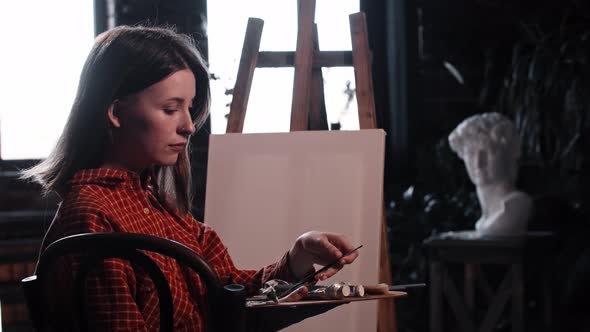 A Young Woman in Art Workshop Takes a Brush and About to Draw a Painting