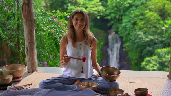 Superslowmotion Shot of a Woman Master of Asian Sacred Medicine Performs Tibetan Bowls Healing