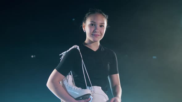 Lady Figure Skater is Holding Her Skates and Smiling