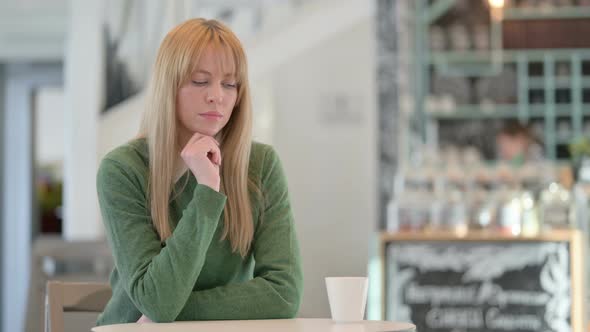 Beautiful Young Woman Sitting in Cafe and Thinking