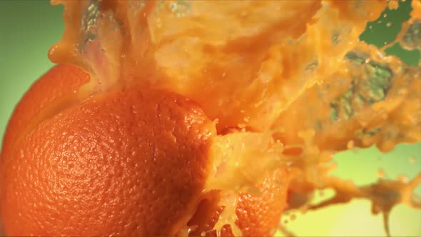 Fresh Orange Fruit Squirting with Juice in Slow Motion in Green Nature Background