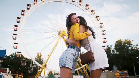 Two Young Women are Smiling Hugging Each Other Talking and Rejoicing Their Meeting While Posing in