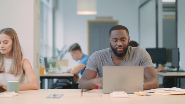 African Man Working on Laptop Computer at Co-working