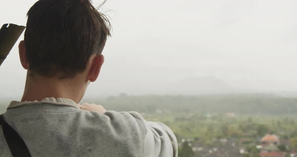 Close Up Shot of a Man on a Viewpoint Pointing at the Panoramic Scenery in the Rainy Valley Below in