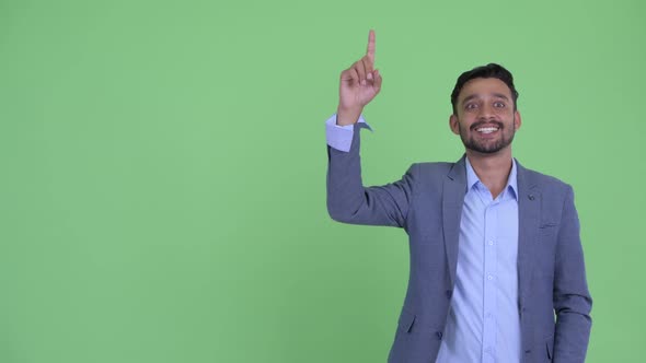 Happy Young Bearded Persian Businessman Thinking and Pointing Up