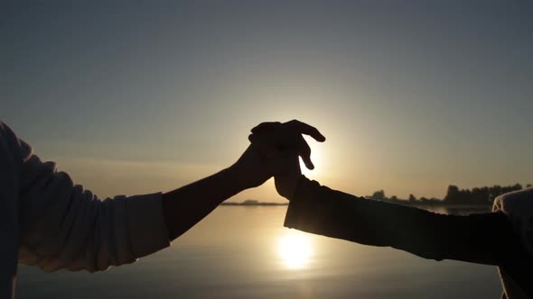 Silhouette of Hands Hold Together at Sunrise