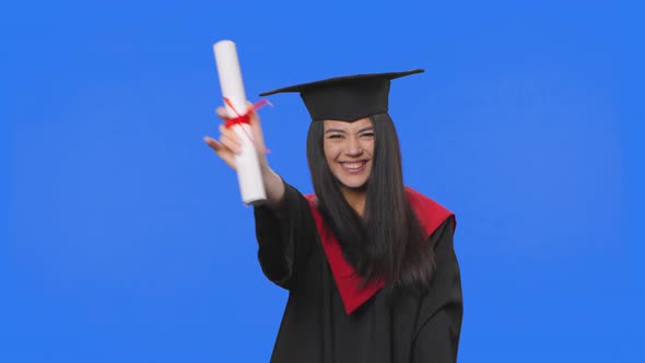 Portrait of Female Student in Cap and Gown Graduation Costume Holding Diploma and Dancing Merrily