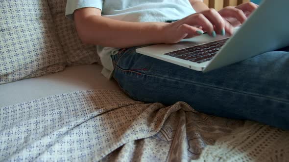 Young Woman Quickly Typing on the Keyboard Using Laptop to Work Lying on the Bed in the Bedroom