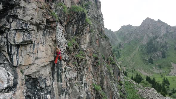 Woman Athlette Climbing on the High Rock in the Mountains