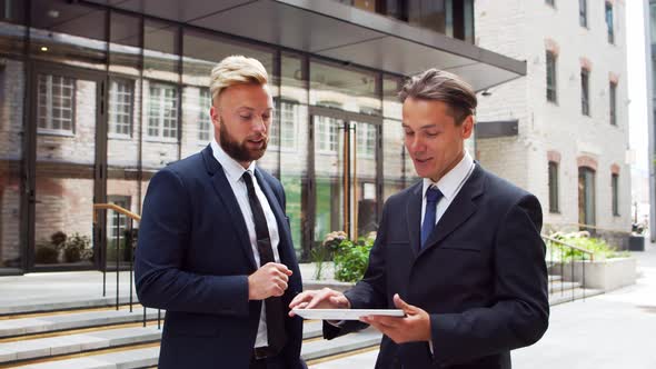 Confident businessman and his colleague in front of modern office building.