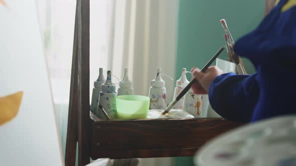 Child Is Cleaning Brush and Putting Into Dye