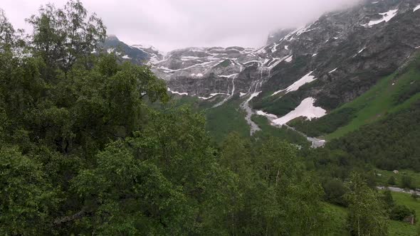 Aerial View Low Flight Over the Forest To High Mountain Waterfalls with Places Not Melted Snow in