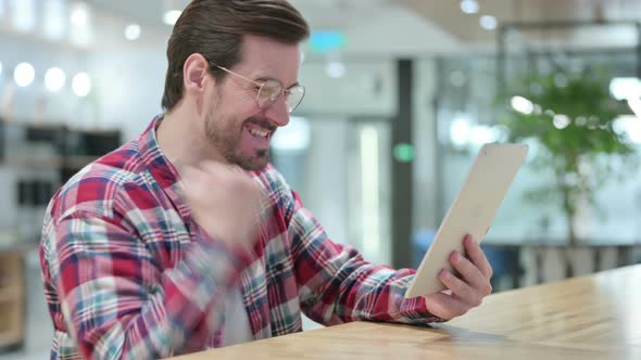 Excited Male Designer Celebrating Success on Tablet