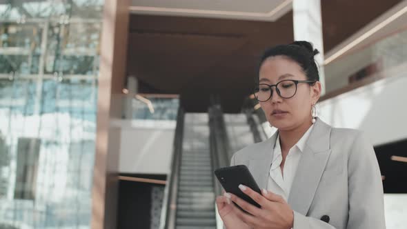 Businesswoman with Mobile Phone Walking in Lobby