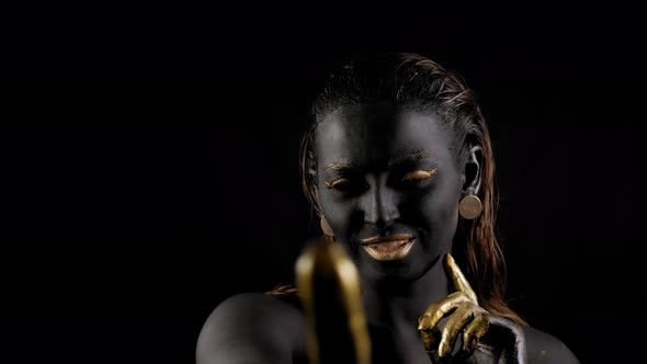 Closeup of a Young Woman with Black and Gold Paint on Her Body