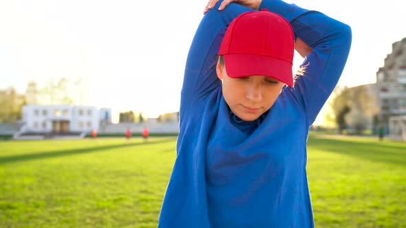 Woman Makes a Warmup Before Jogging Through the Stadium at Sunset