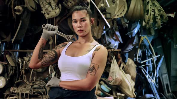 Attractive young woman mechanical worker repairing a vintage car in old garage.