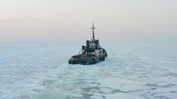 View of a Tug Making Its Way Through the Ice at Sunset