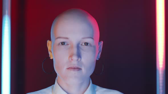 Bald Woman Looking at Camera in Studio with Flickering Neon Lamps