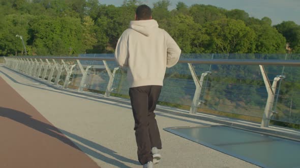 Rear View of Active Sporty African American Athlete Running Outdoors at Sunrise