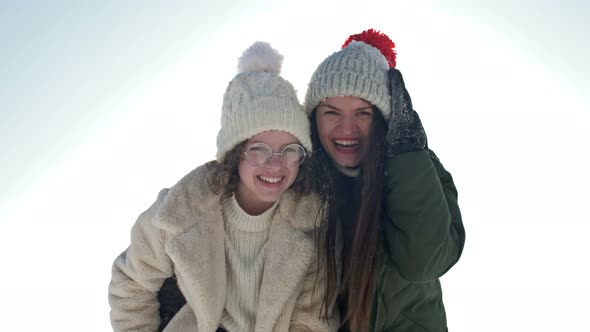 Portrait of Two Cheerful Girlfriends or Sisters on the Background of a Sunny Winter Day