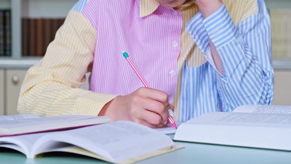 Closeup of Female Hands Writing with Pencil in Notebook Books on the Table alt