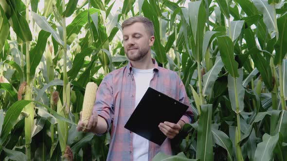 Young Happy Farmer Juggling a Head of Organic Corn