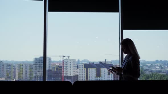 Side View Silhouette of Executive Woman Walking Along Hall Near Windows