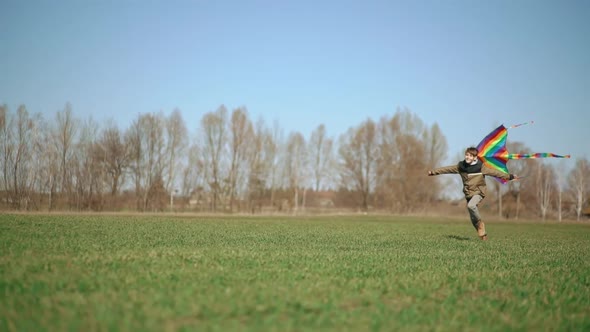 A Boy Runs Across a Green Field with a Kite