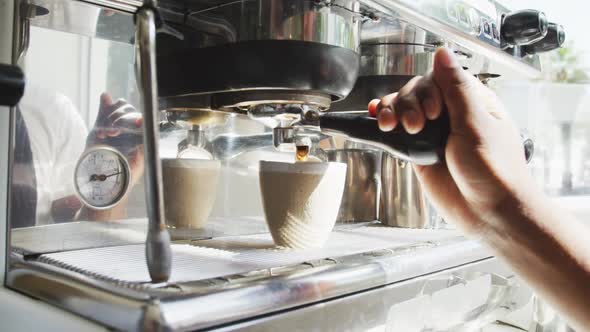 Close up of african american male barista making coffee at cafe