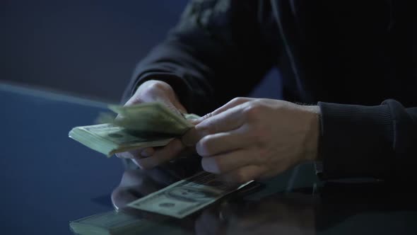 Hands of Contract Killer or Bank Robber Counting Money Paid for Committing Crime