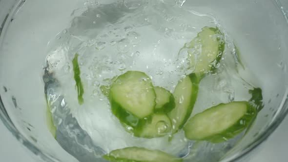 Cucumber Slices Fall Into the Water, Slow Motion. Several Pieces of Fresh Green Cucumber