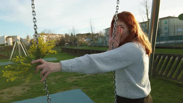 Young Beautiful Red Hair Girl Enjoys at the Park Playing with the Swing